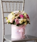 Flowers in a hatbox with roses and lisianthus in addition to peony varieties of roses